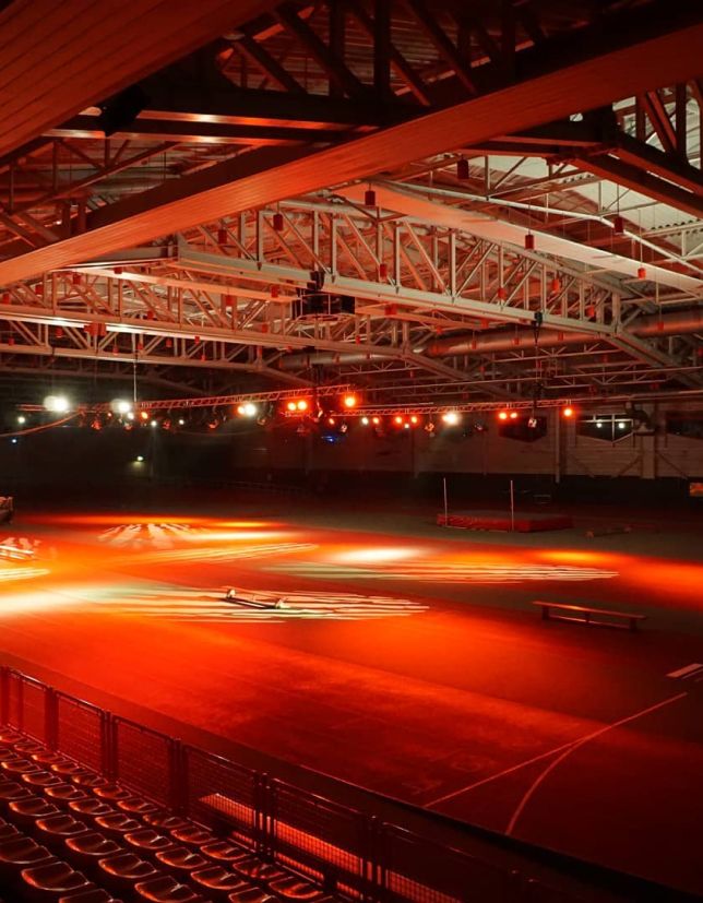 Rot beleuchtete leere Sporthalle mit komplexer Dachkonstruktion.Rot beleuchtete leere Sporthalle mit komplexer Dachkonstruktion.
