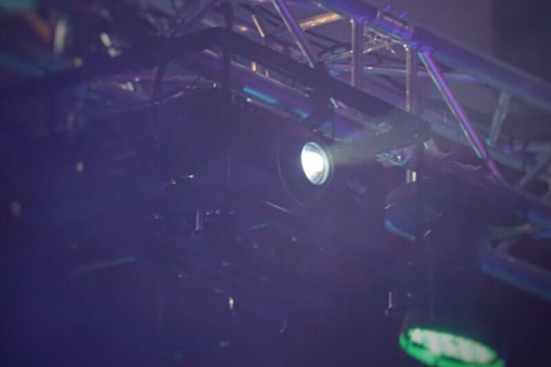 Ein Scheinwerfer leuchtet aus einer Metallkonstruktion in einer schwach beleuchteten Umgebung.